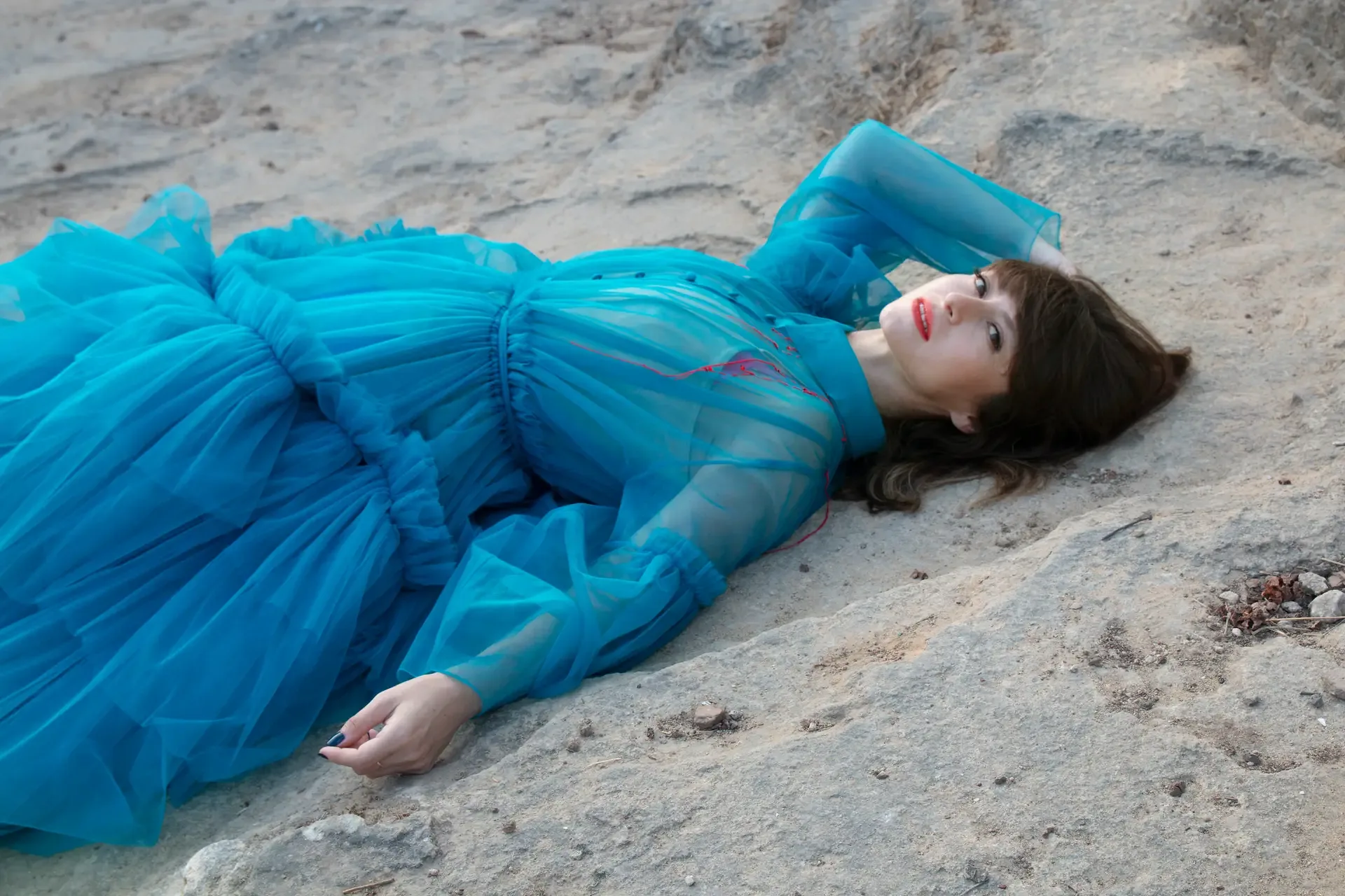 Aviya Kopelman in a blue dress lying on rock